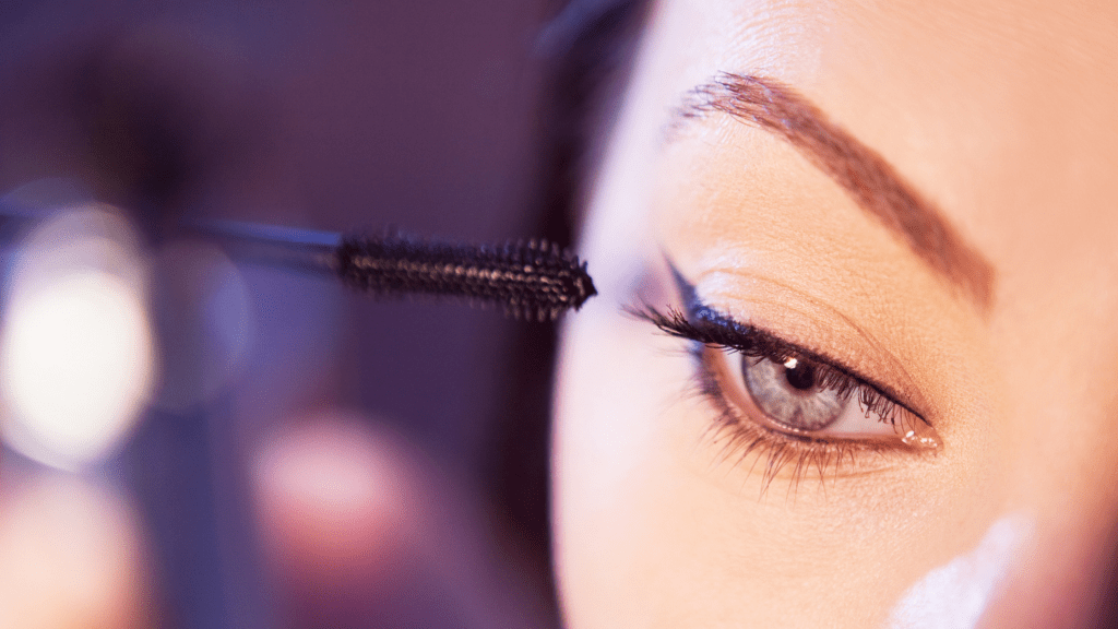Woman applying eye makeup mascara closeup