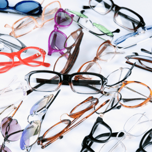 styles of eyeglasses laying on a table including plastic frames, metal frames, sunglasses at The Eye Center